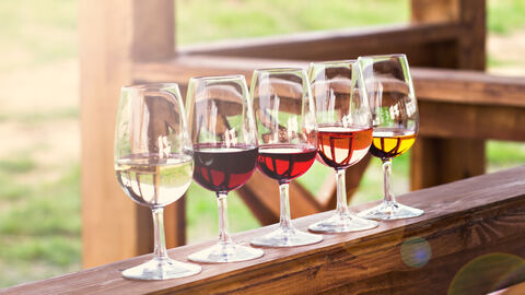 Weingläser aufgereiht auf einem Holzbalken