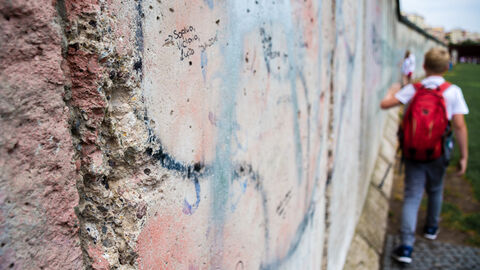 Junge geht an Resten der Berliner Mauer entlang