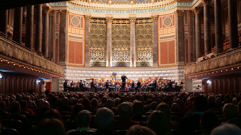 Ein Orchester gibt vor einer großen Anzahl an Menschen ein Konzert