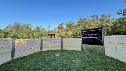 Saufang Innenansicht - Halbrunder Holzaufbau auf Wiese mit Öffnung an einer Stelle