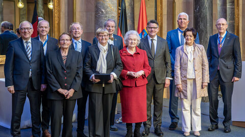 Elf Personen stehen nebeneinander und halten ihre Auszeichnungen in der Hand.