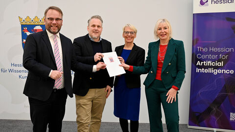 Zwei Männer und zwei Frauen stehen nebeneinander und halten eine Urkunde in der Hand.