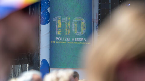 Auf einem großen Bildschirm werden die Ziffern 110 angezeigt. Die Ziffern werden aus verschiedenen Schlagwörtern gebildet, die die Hessische Polizei am besten beschreiben.