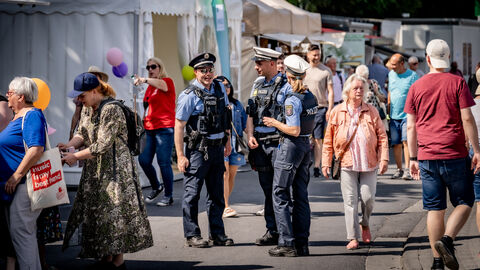 Innenminister und Polizei ziehen positive Bilanz der Sicherheit auf dem Hessentag Drei Einsatzkräfte unterhalten sich - um sie herum sieht man Stände und Besucher des Hessentags